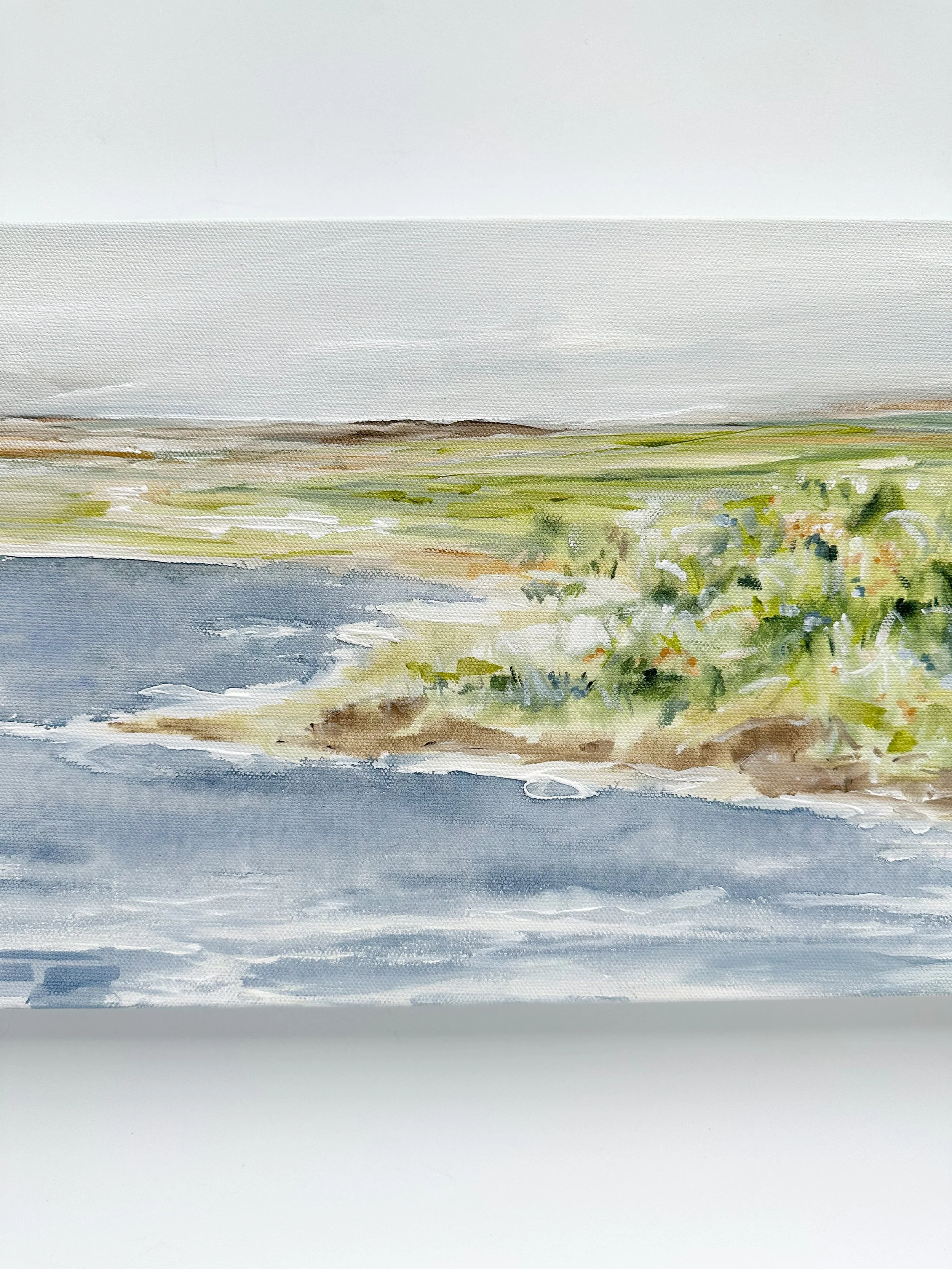 Horizontal original landscape painting with calm blue water and green shoreline