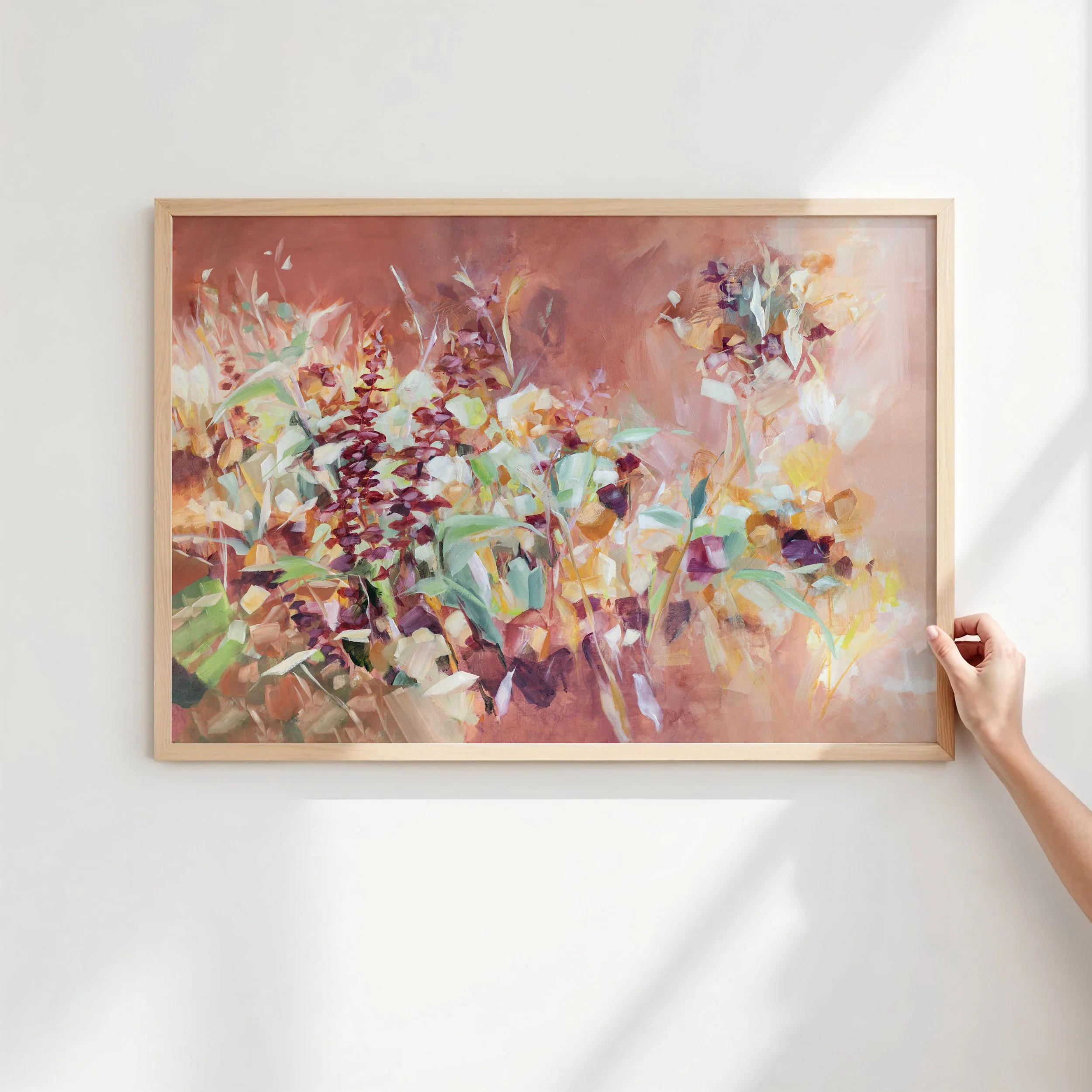 Hand styling a framed abstract floral wall art print by Kendra Castillo in a light-filled home.