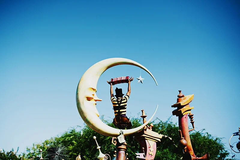 disneyland parade guy sitting on crescent moon