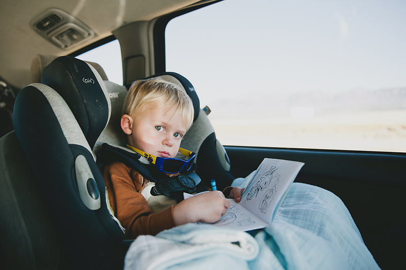 Little boy traveling in a car coloring in coloring book