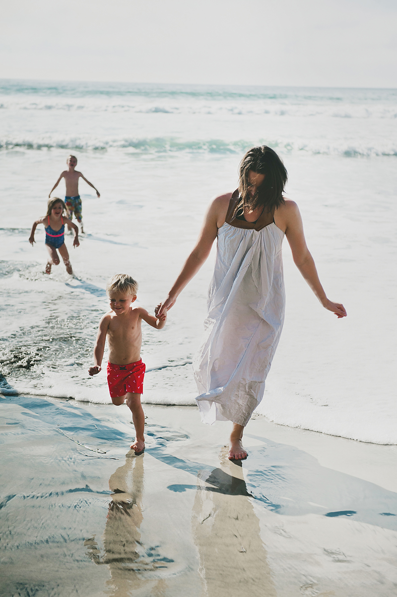 mom running with son on ocean beach