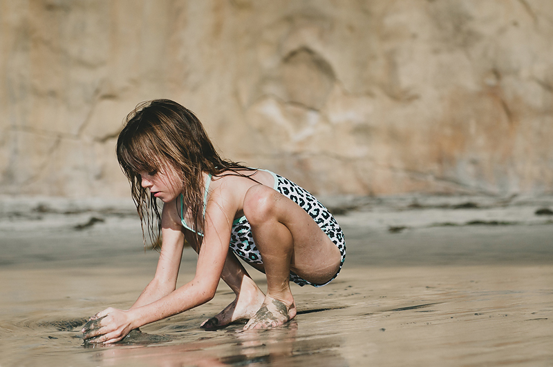 little girl playing in sand on California beach