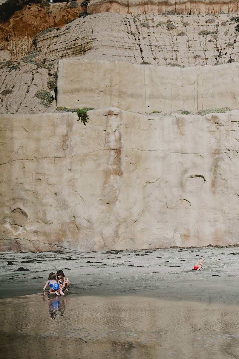 kids playing at base of cliff on california beach