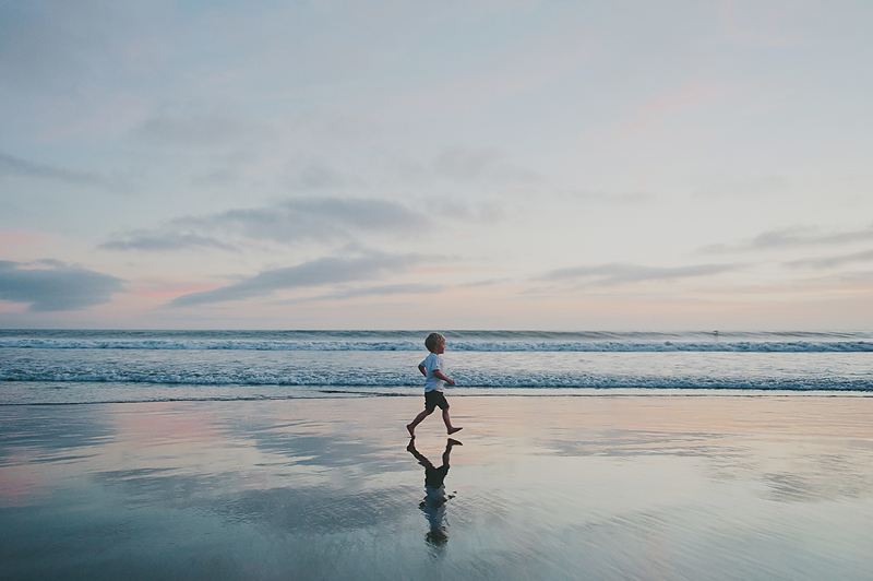 boy running on beach at sunset in california