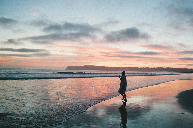 woman walking on beach in California at sunset
