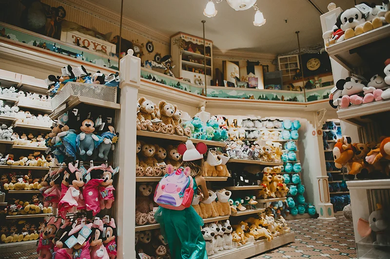 little girl in princess costume wearing unicorn backpack in Disneyland gift shop