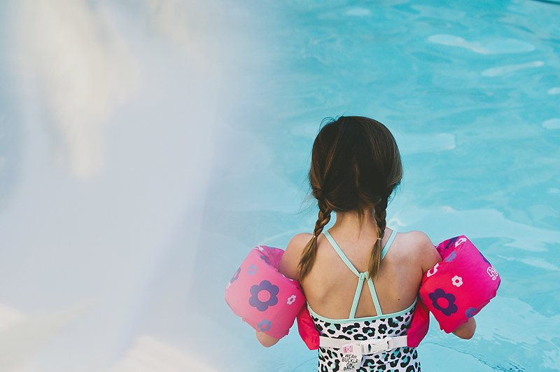 girl with braided pigtails wearing lifejacket in pool
