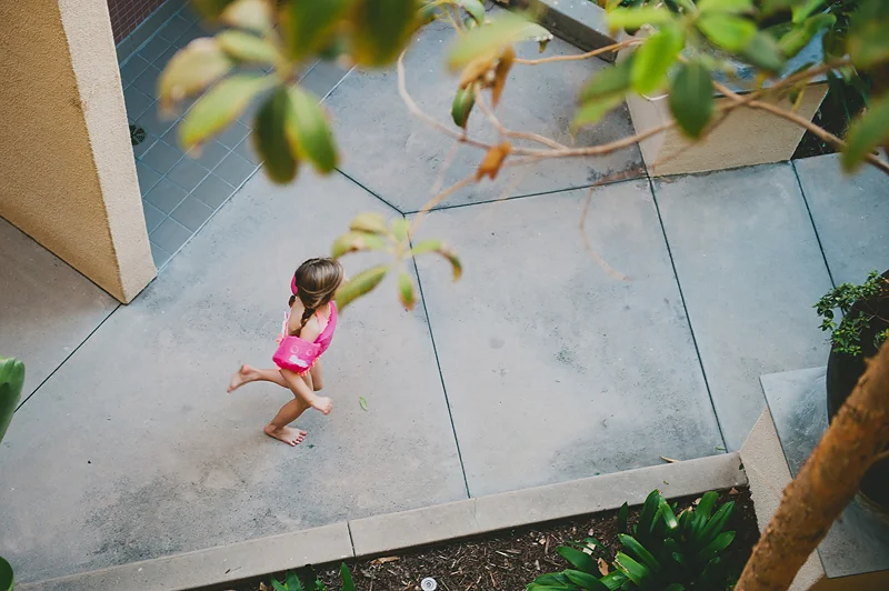 girl in swimsuit and lifejacket running to pool
