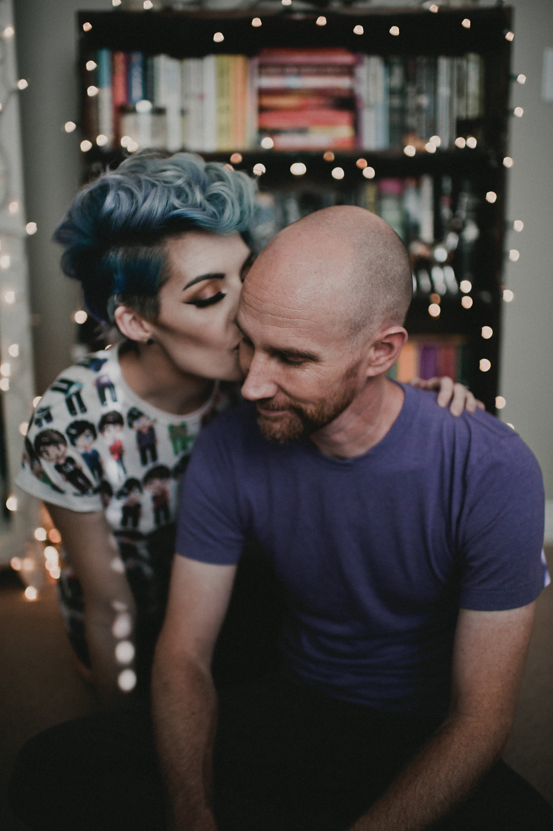 Couple in front of bookshelf with Christmas Lights