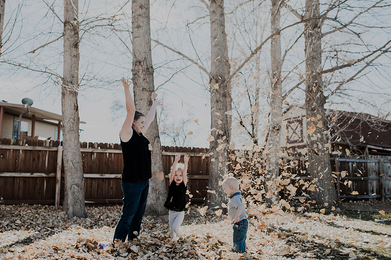 Mom and daughter throwing leaves in the backyard
