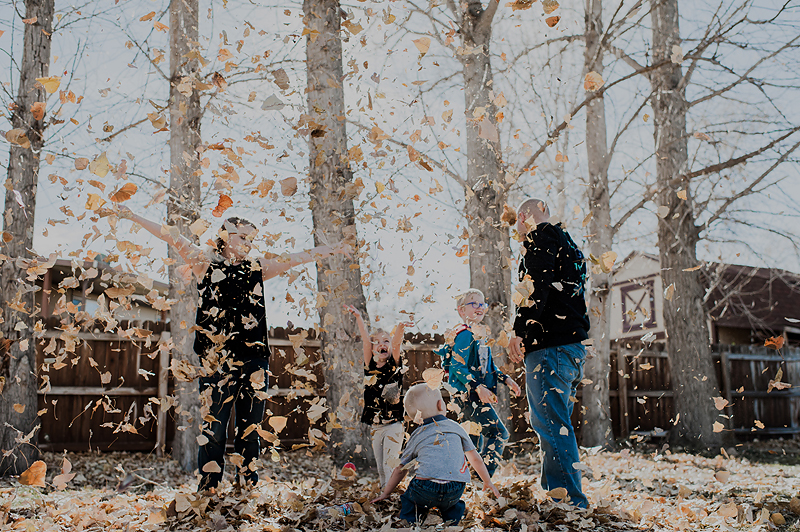 Family throwing leaves in the backyard