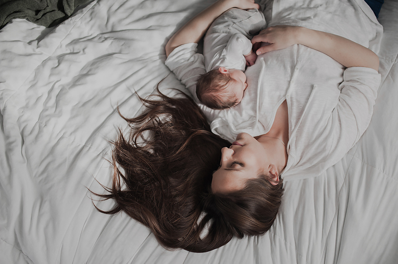 Mom lying on bed holding newborn baby boy