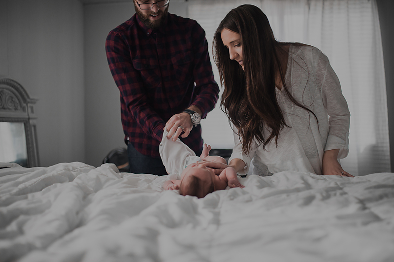 Newborn baby boy getting clothes changed by parents