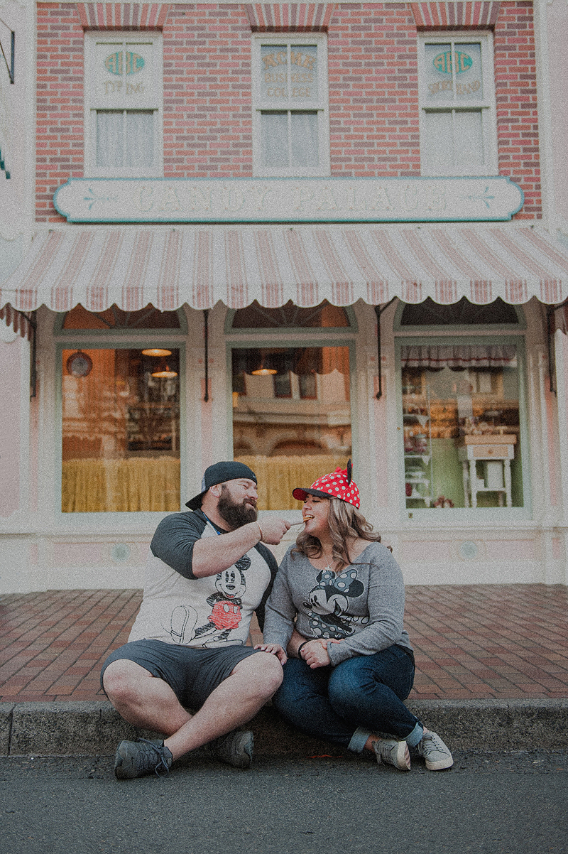 Couple eating churros and people watching on disneyland main street