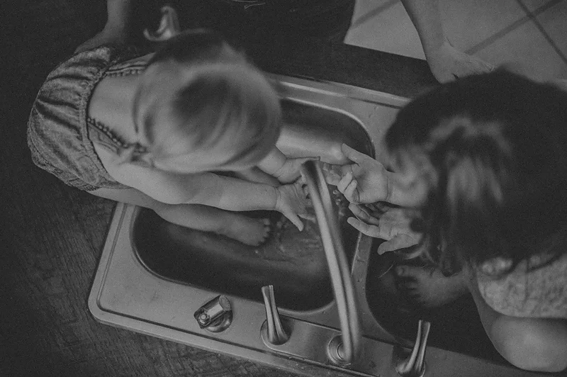 Little girls playing in water in the sink