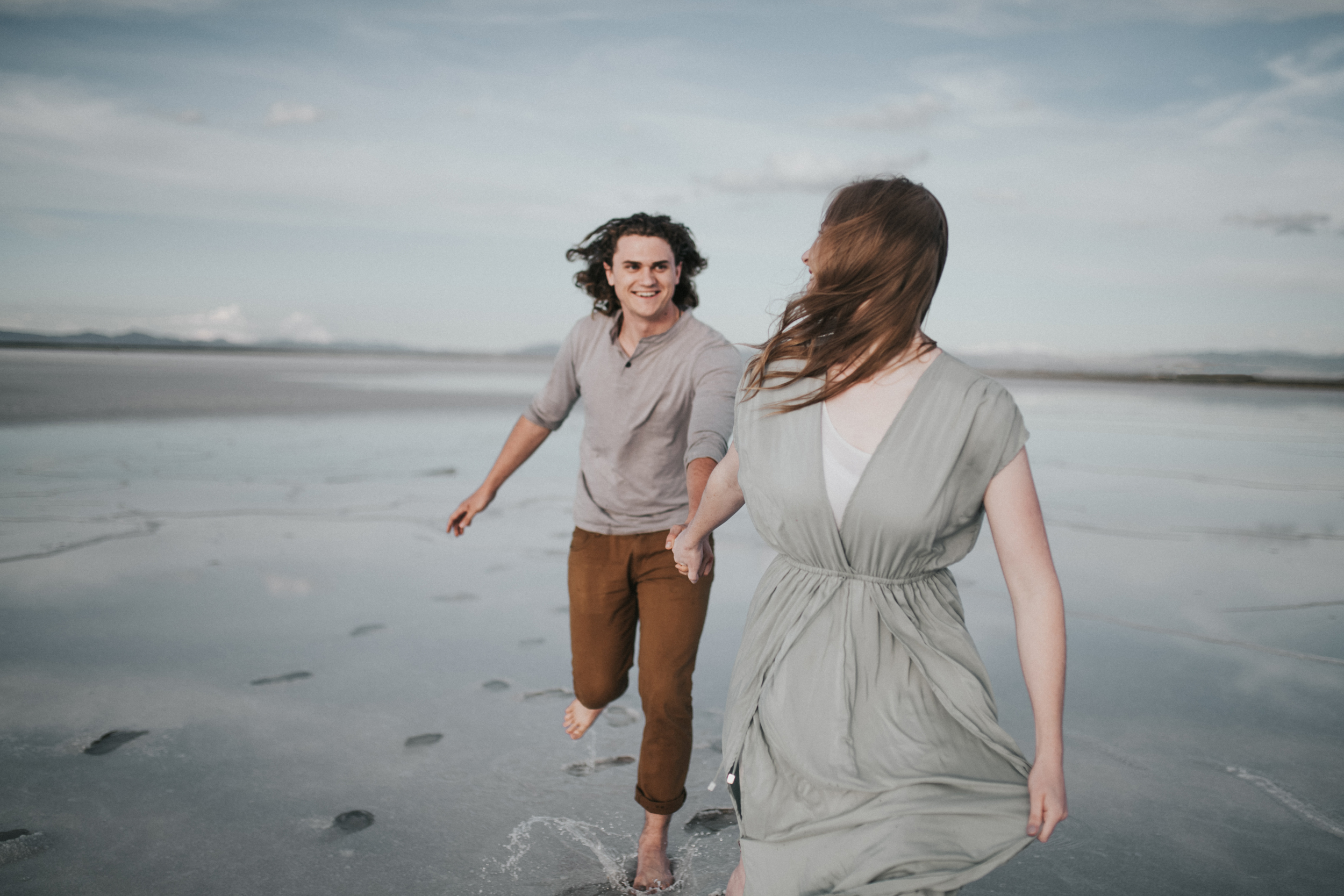 Couple running holding hands at salt flats