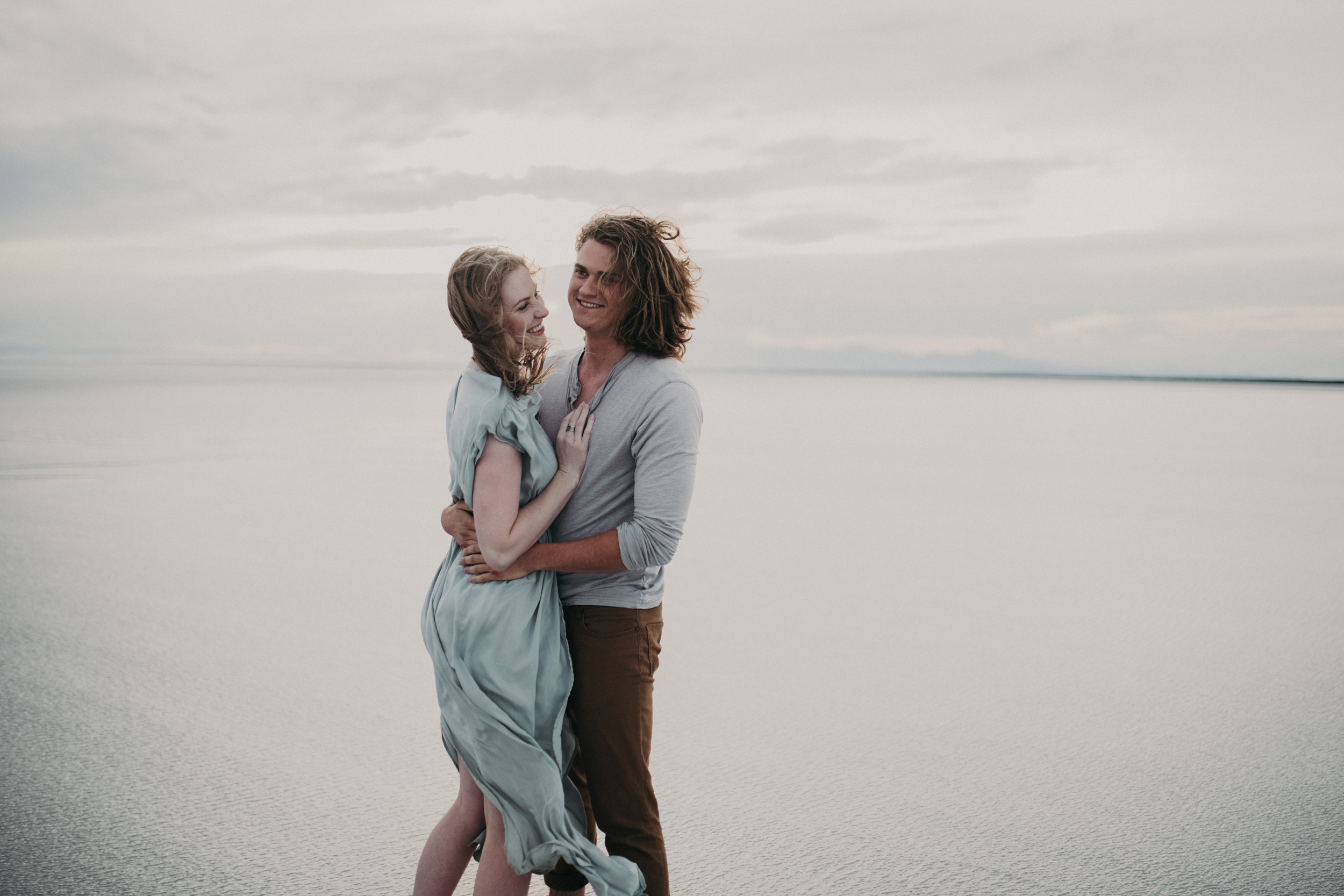 Couple laughing together with water and mountain background