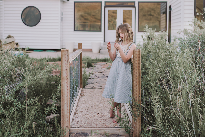 girl wearing blue striped dress on bridge playing with hair
