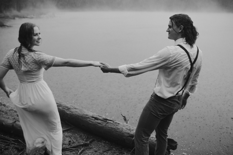 Couple holding hands in rain in front of foggy lake