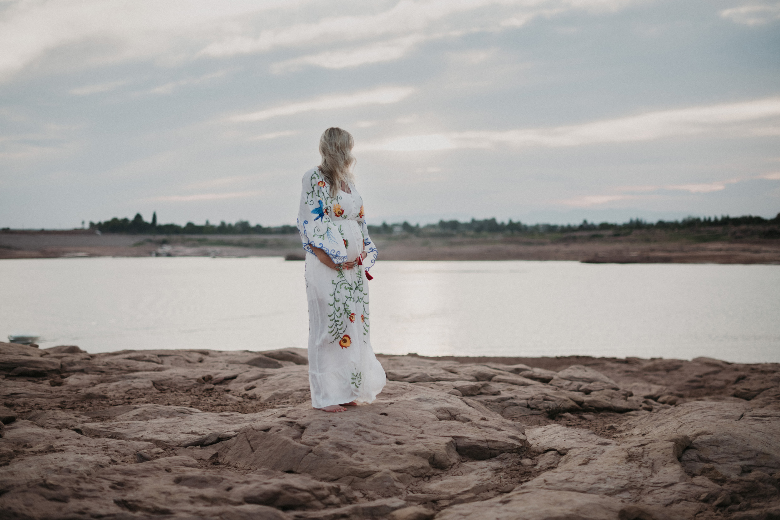 Pregnant woman in front of lake on rocks