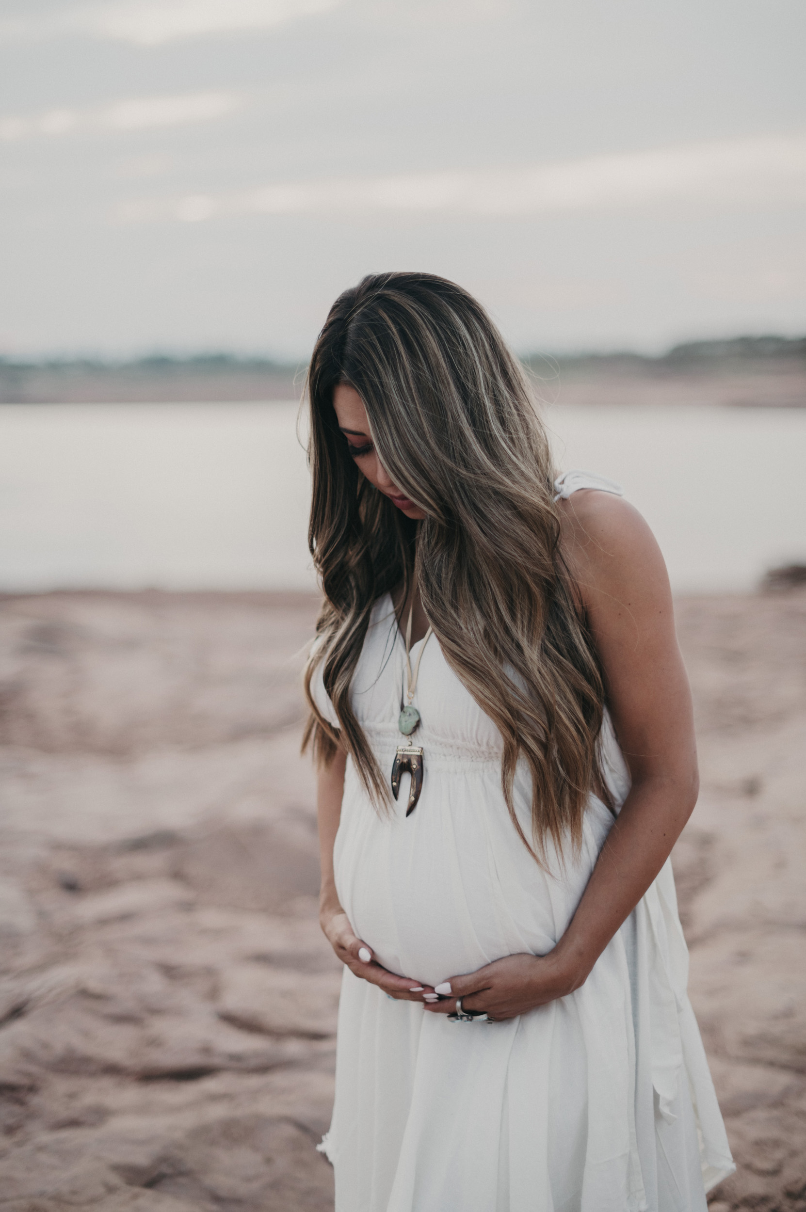 Pregnant woman in front of lake on rocks