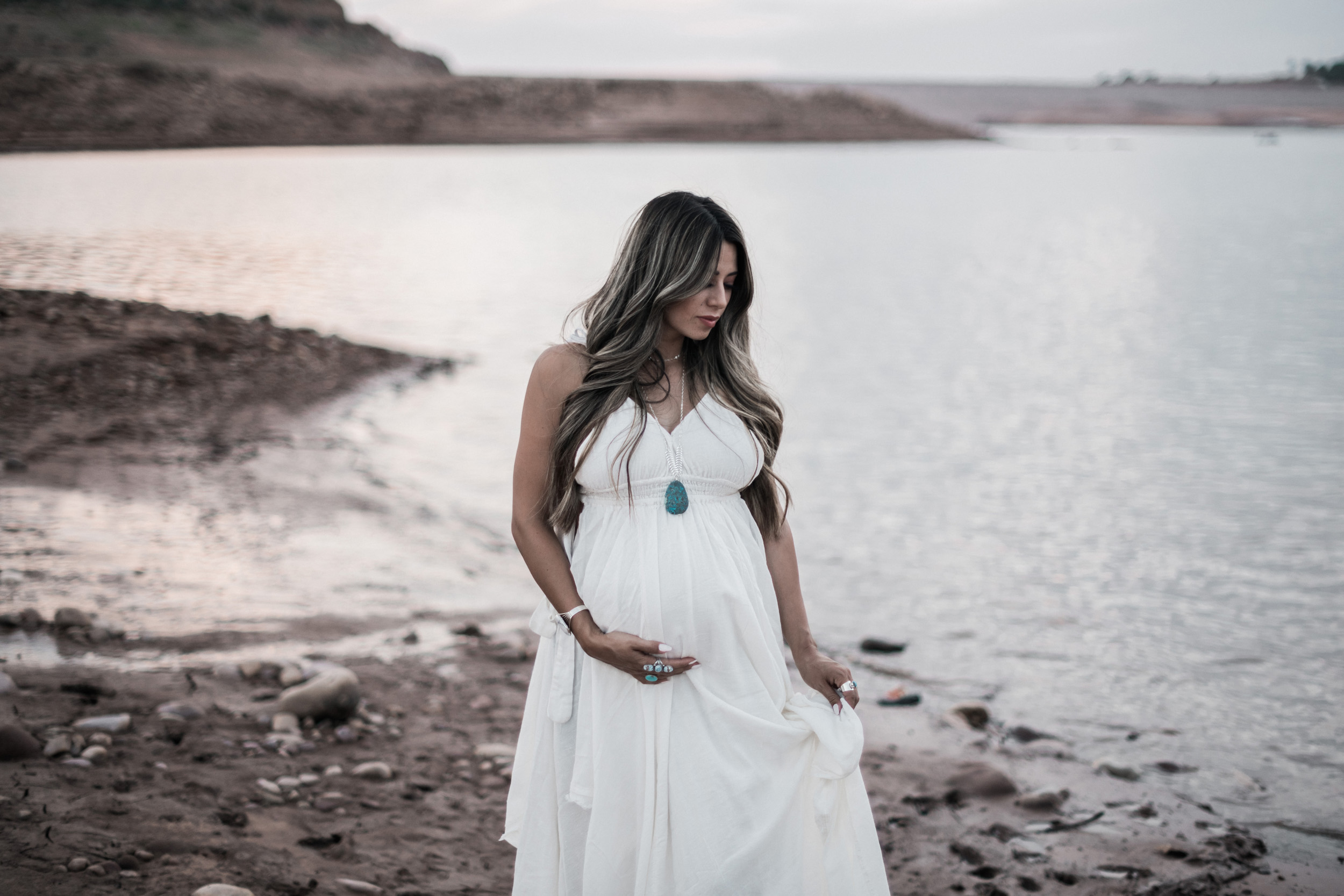Pregnant woman on beach at lake turquoise necklace