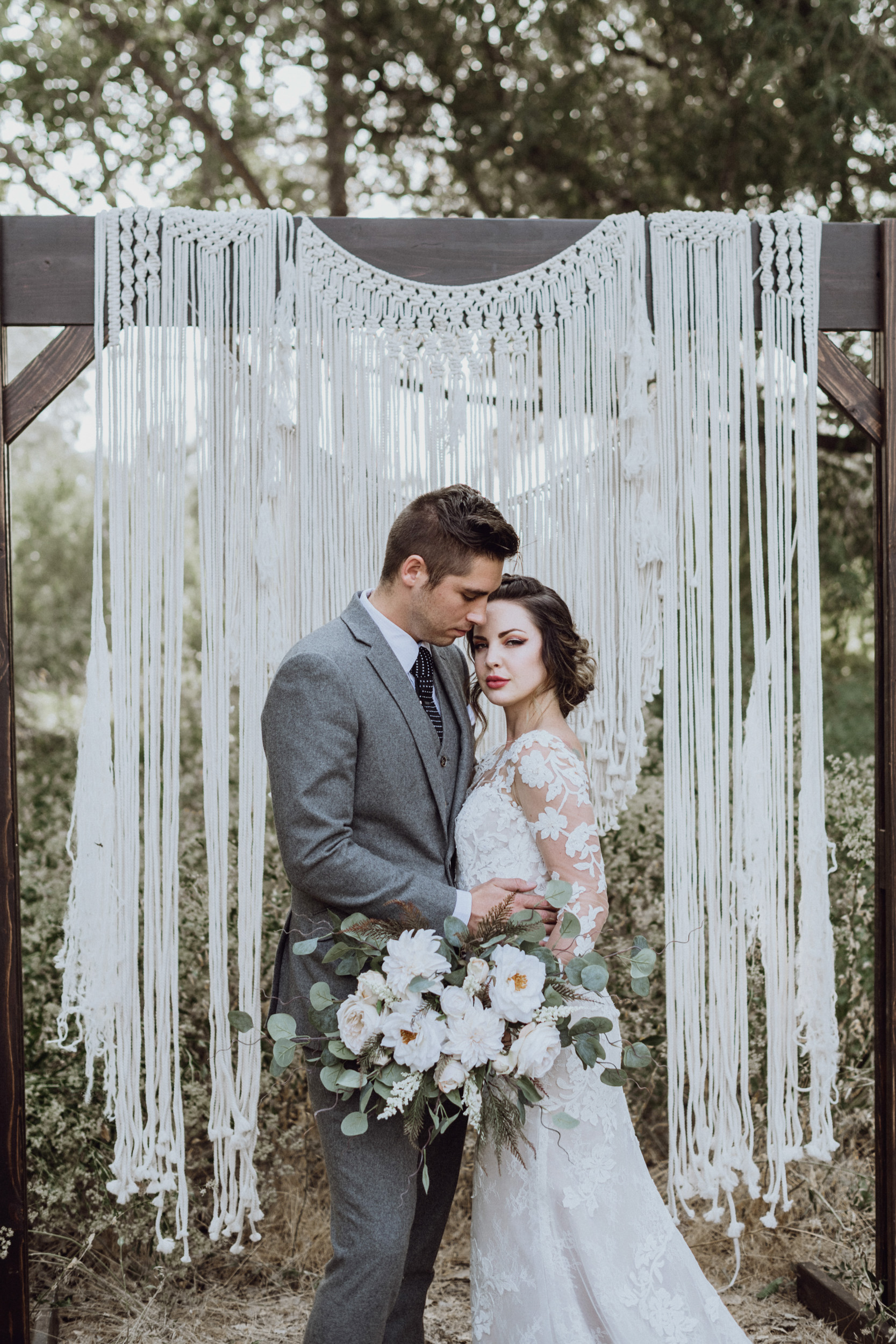 Groom holding bride in front of Macrame 
