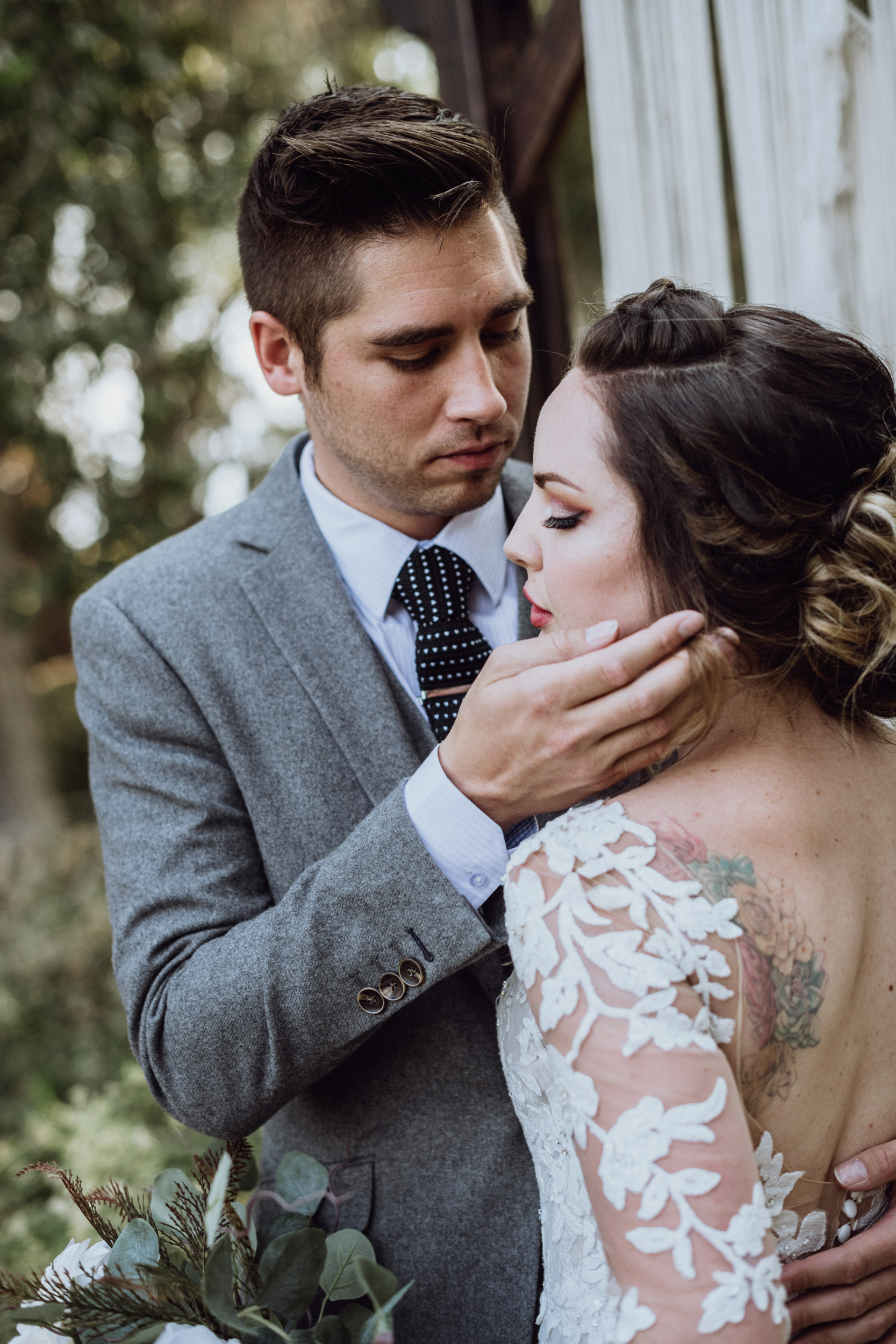 Groom touching brides face in front macrame