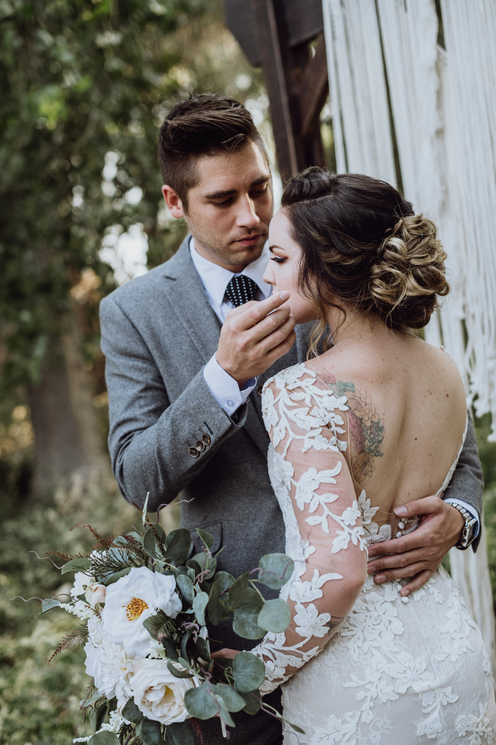 Groom touching brides face in front macrame