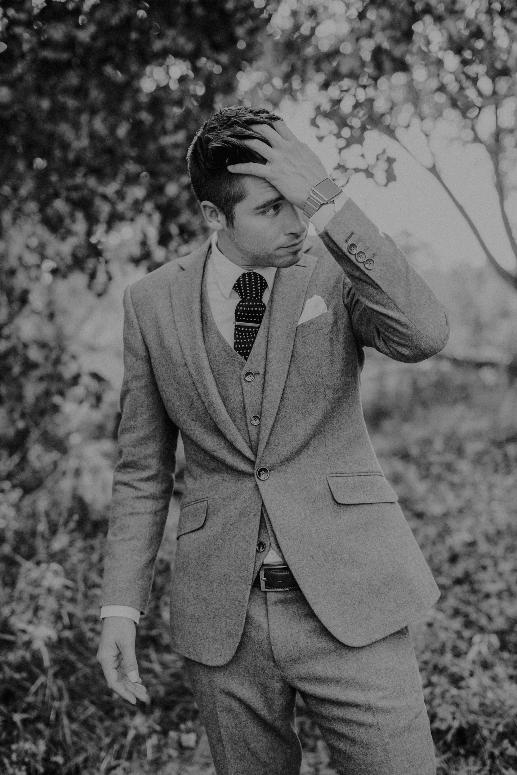 Groom in grey suit standing in grassy field