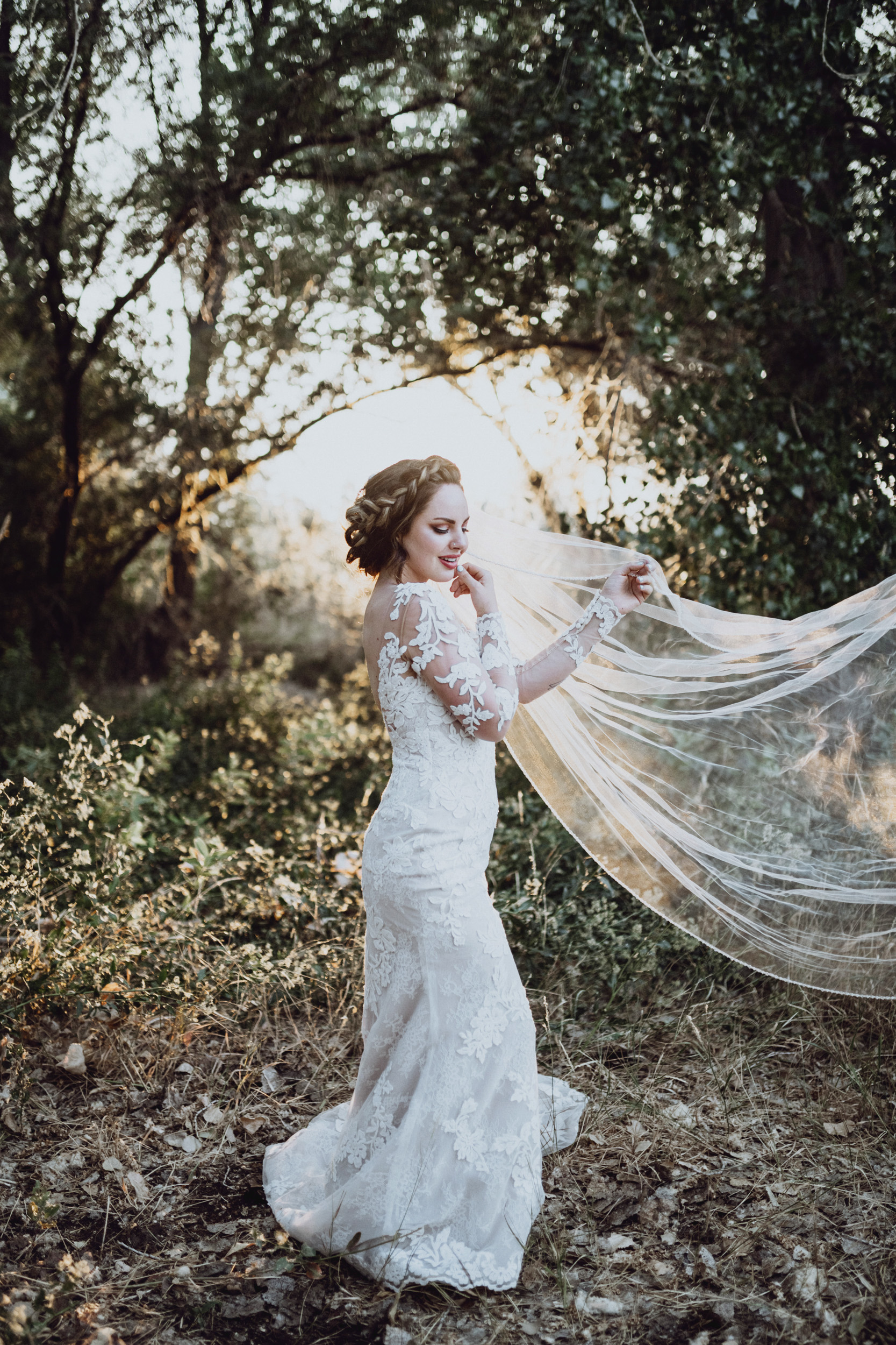 Bride in lace dress standing in grassy field 