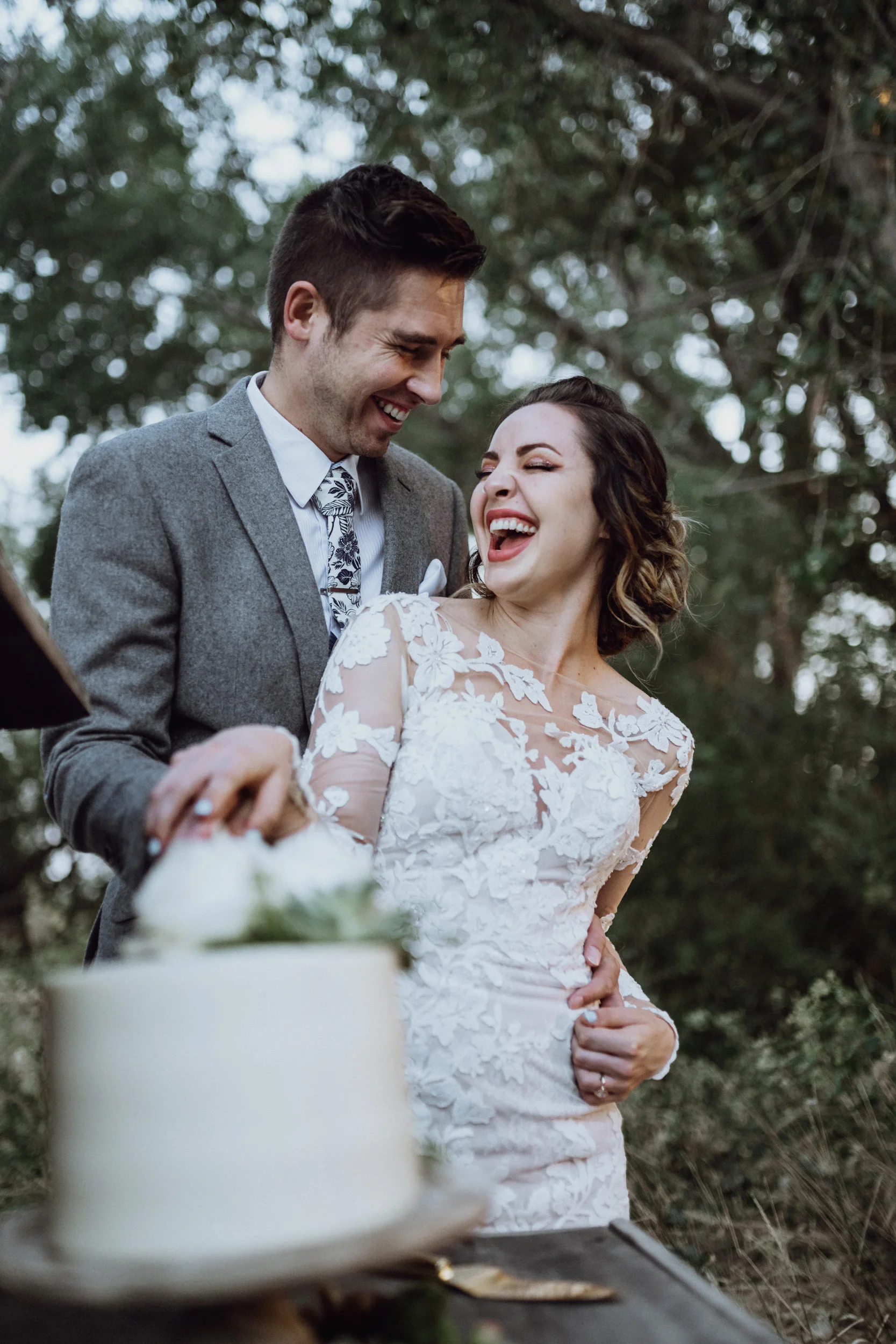 Bride and groom cutting cake in grassy field