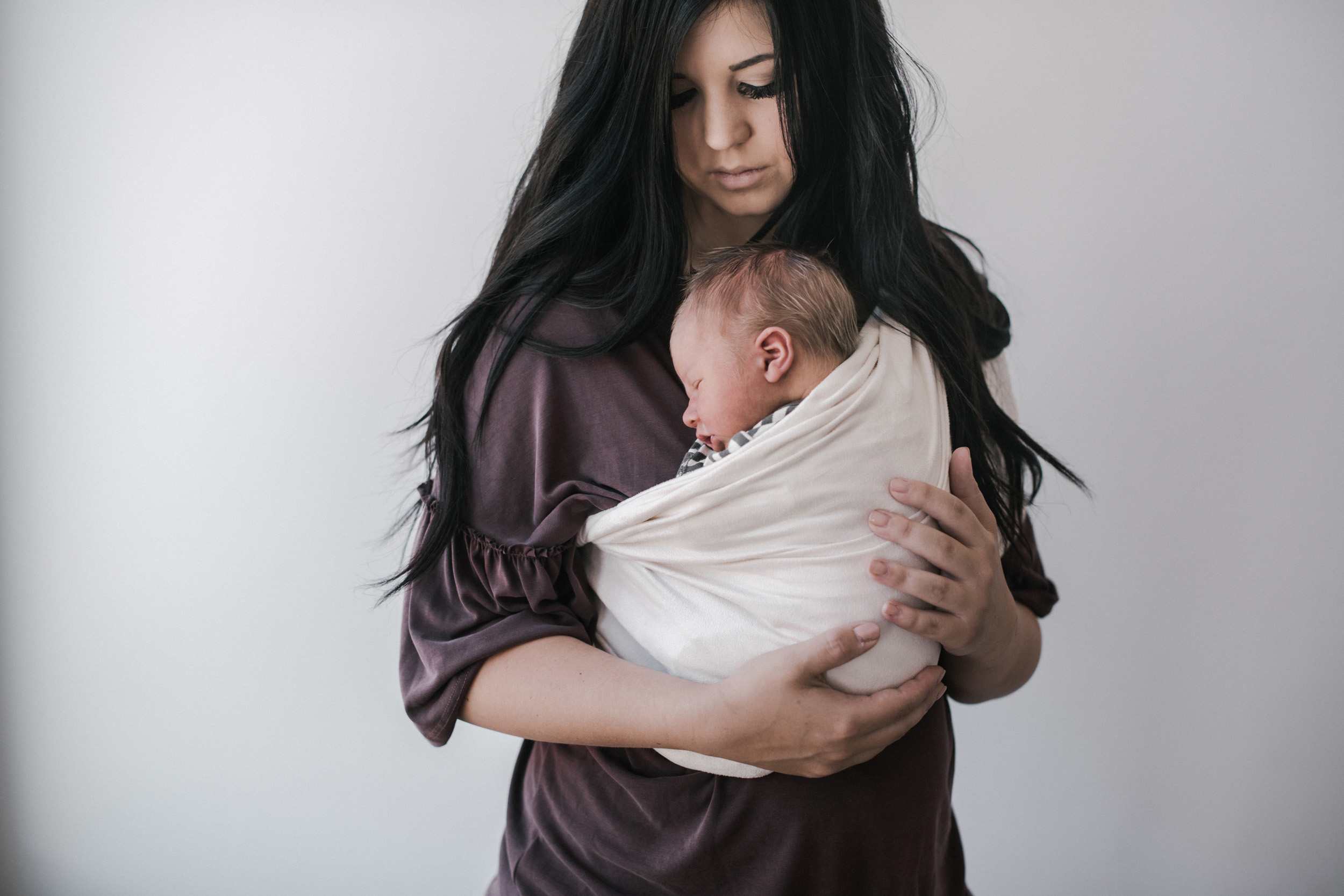 newborn baby boy in baby wrap being held by mom