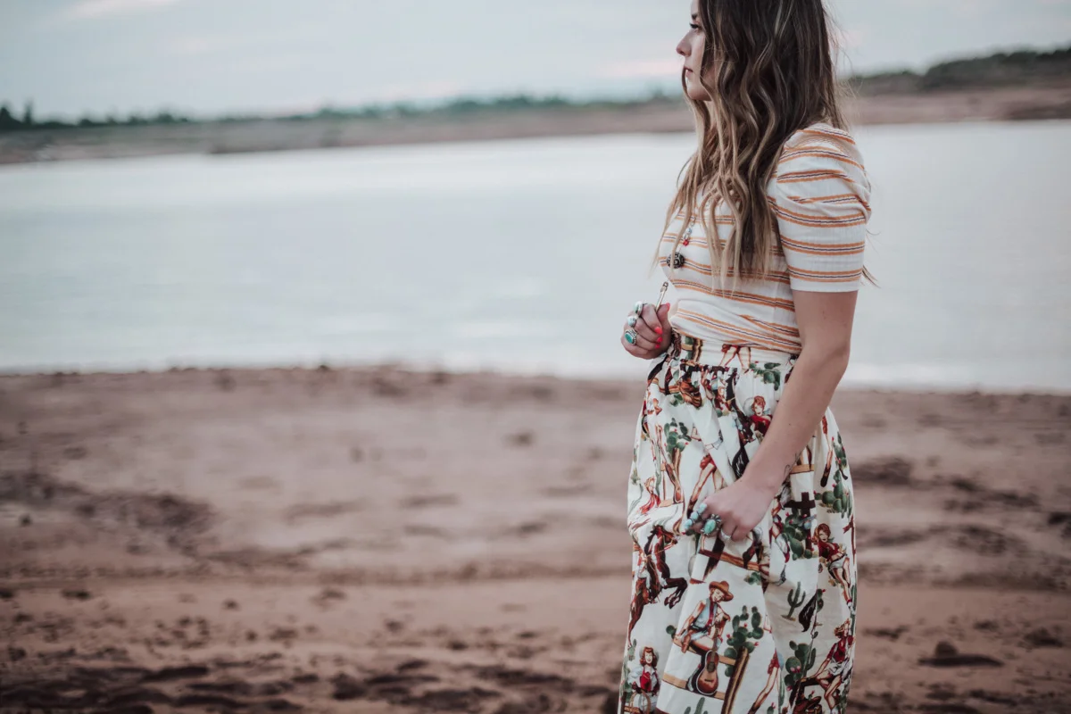 girl standing in front of lake and red rock