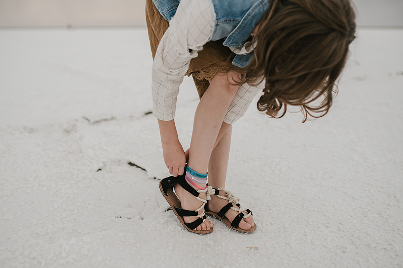 girl with ankle bracelets fixing sandal