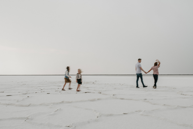 parents walking holding hands with daughters on salt flats