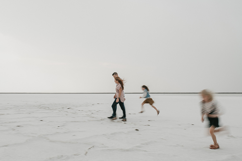 parents walking with daughters running on salt flats