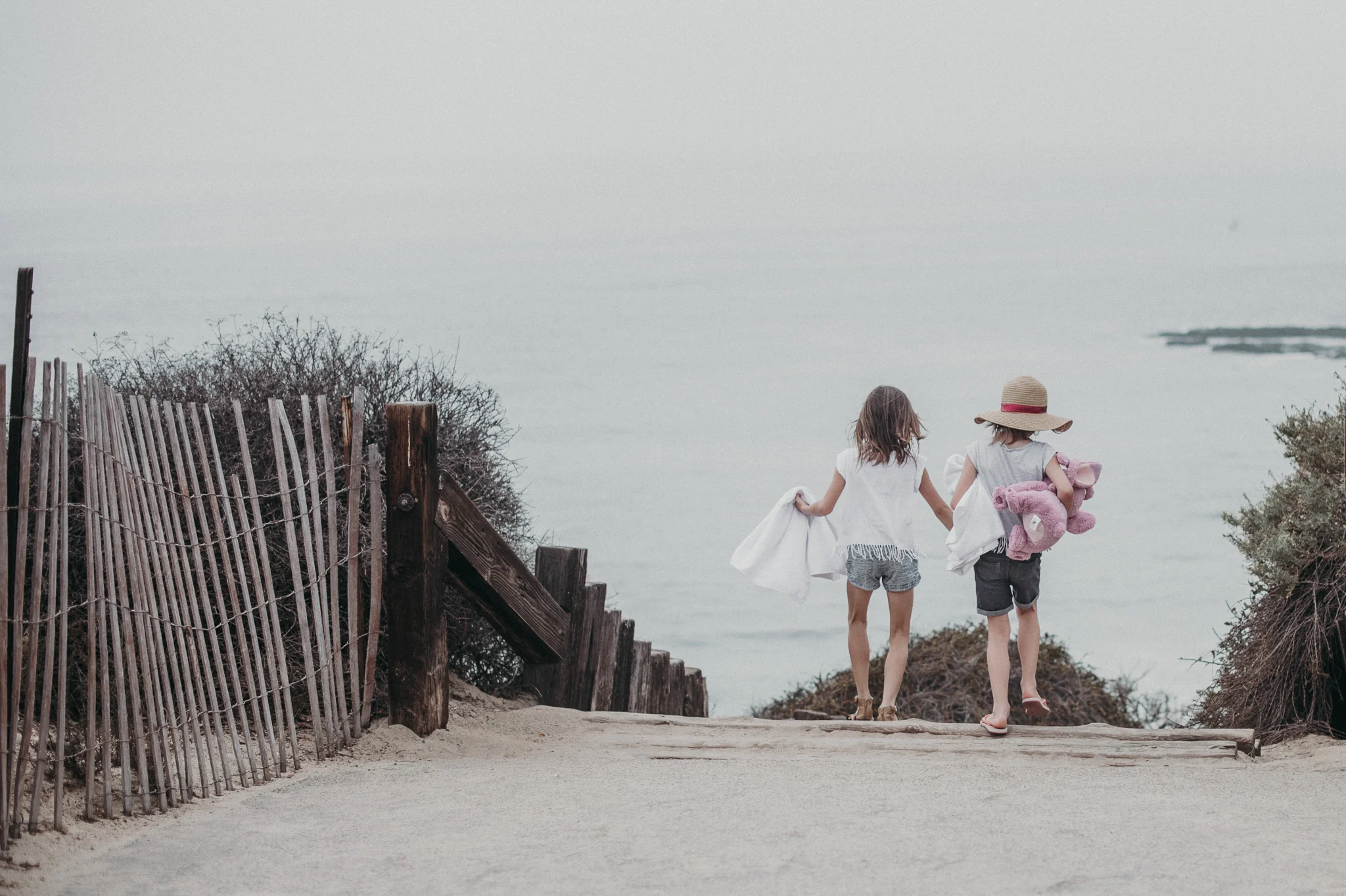 Two girls holding hands walking to the beach