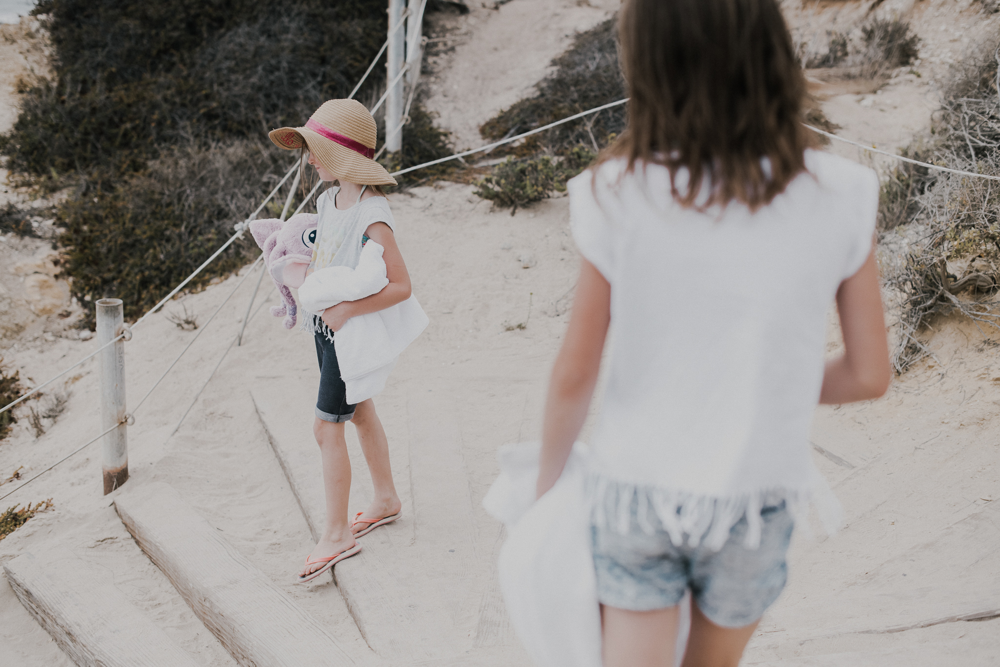 Little Girl with hat walking with mom to the beach 