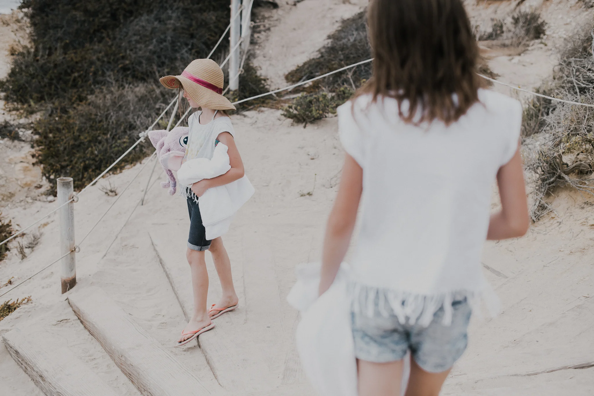 Little Girl with hat walking with mom to the beach