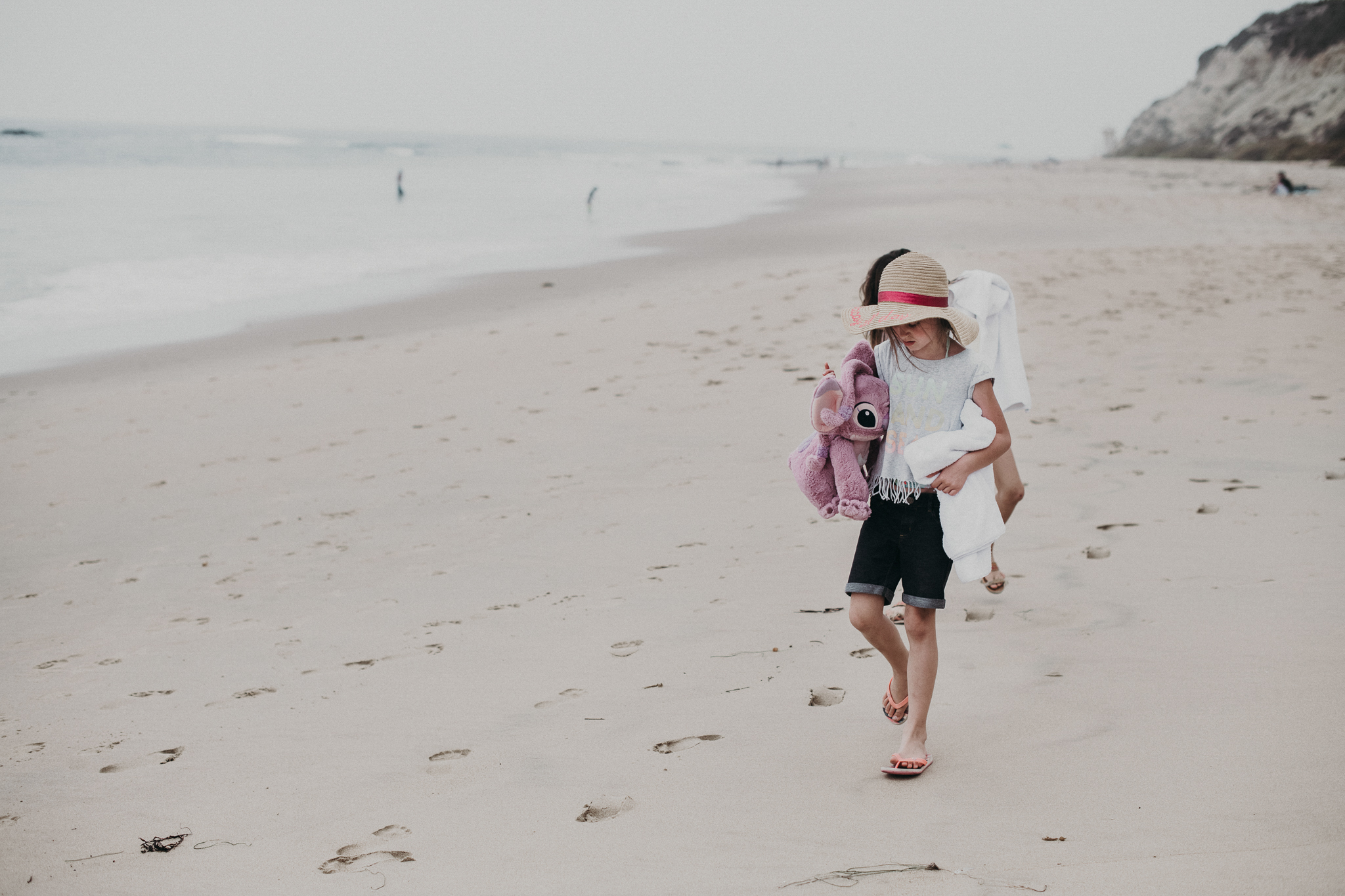 little girl with hat walking along the beach
