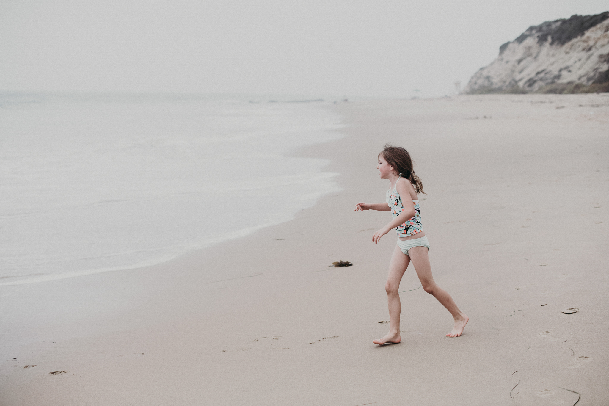 Little girl running towards the ocean in California 