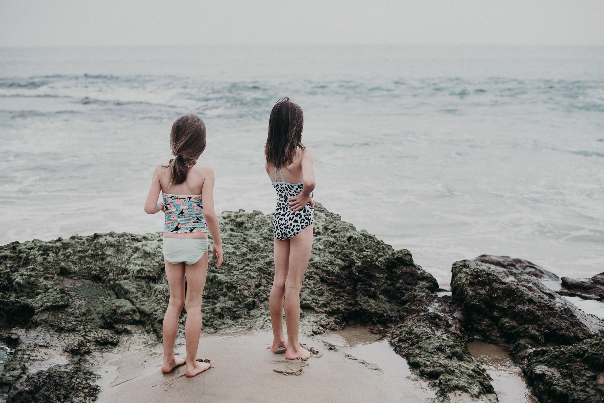 Girls walking along the beach looking out at the water