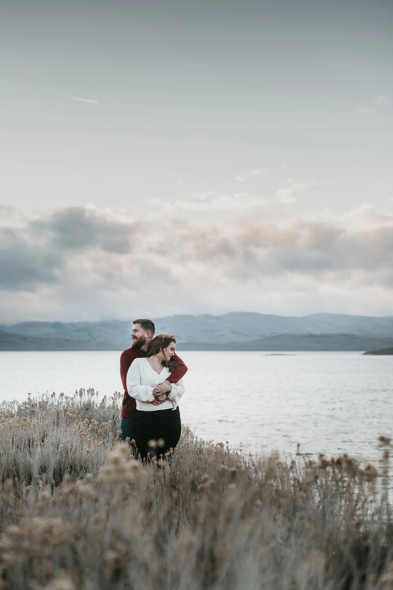 Adventurous couple hugging looking over water