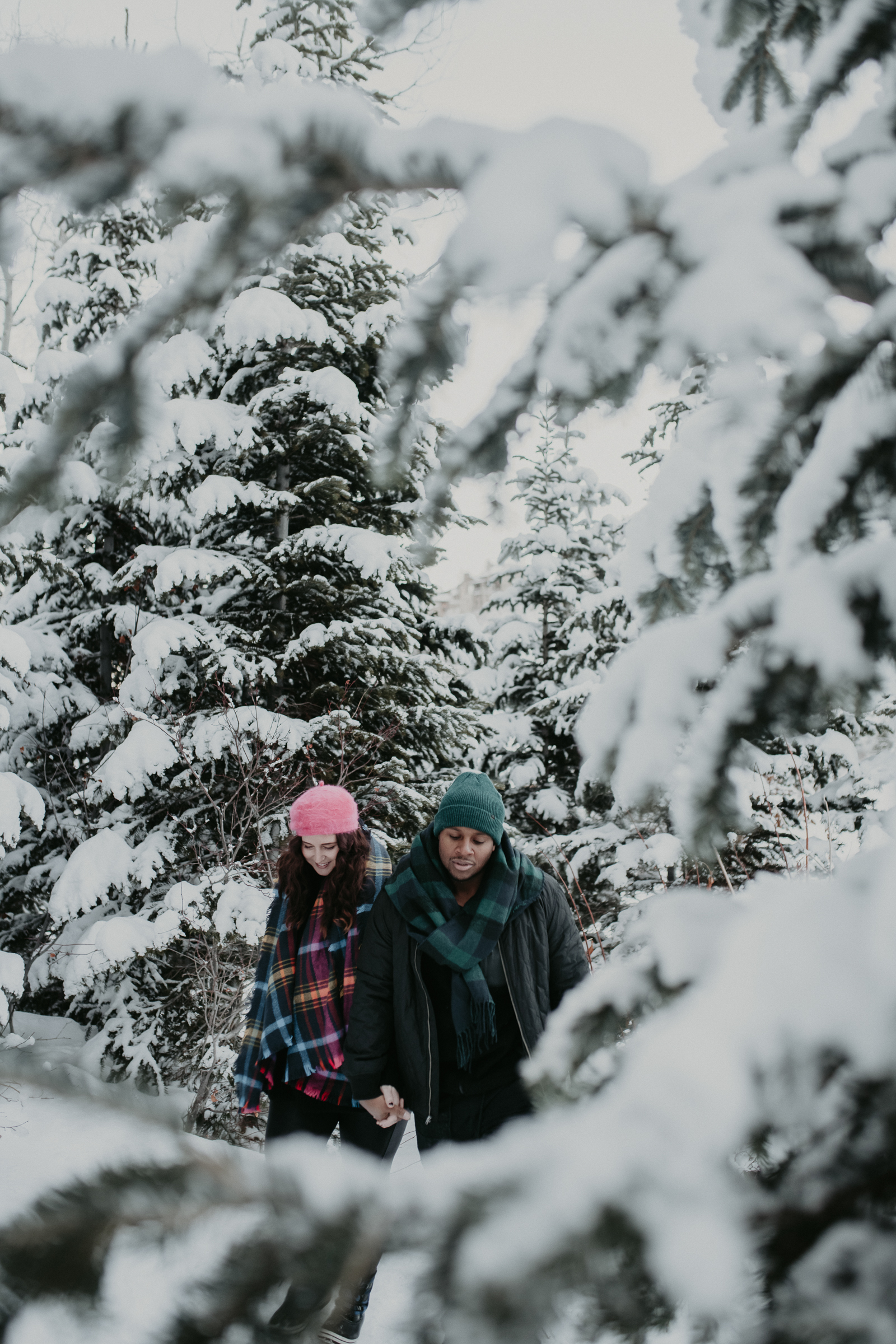 Couple walking through trees in snowy mountains 