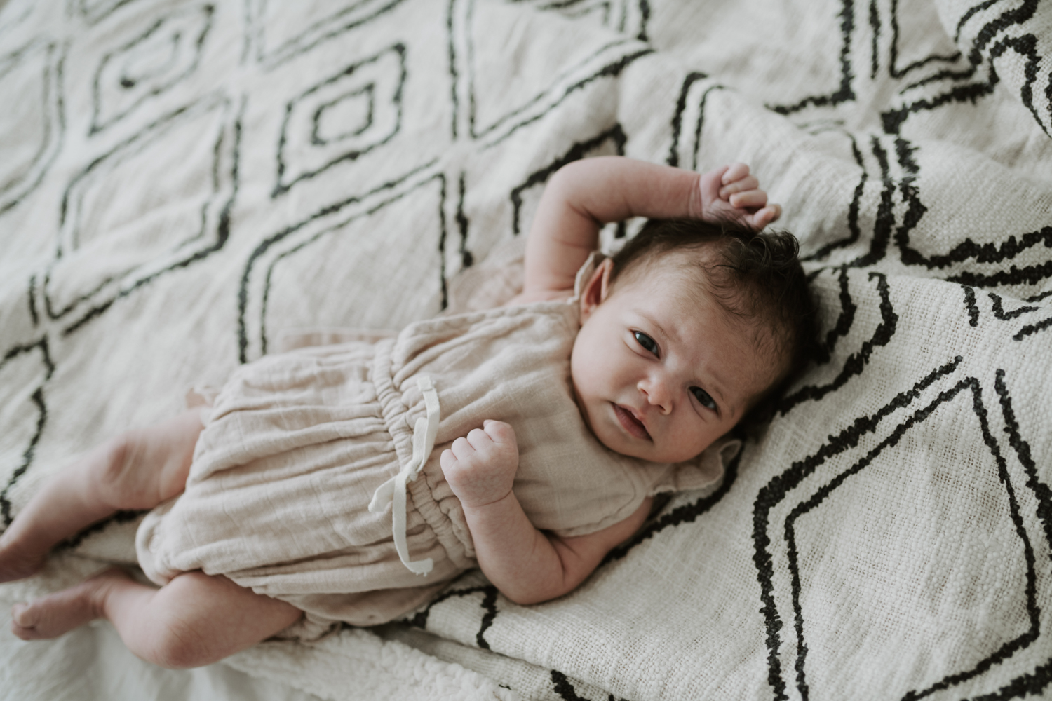 Newborn baby girl laying on diamond pattern blanket