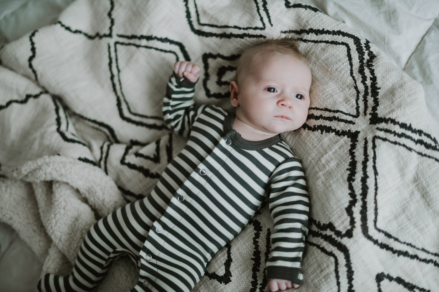 Newborn baby boy laying on diamond pattern blanket