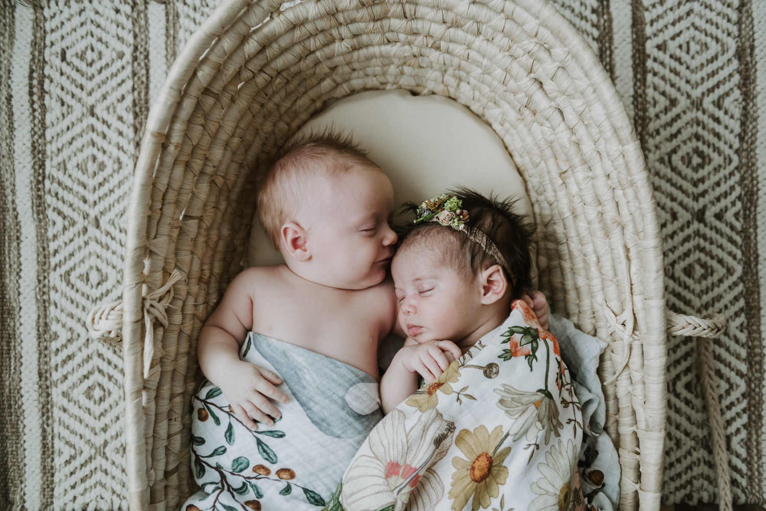 Newborn baby girl and boy wrapped in blankets while sleeping in bassinet