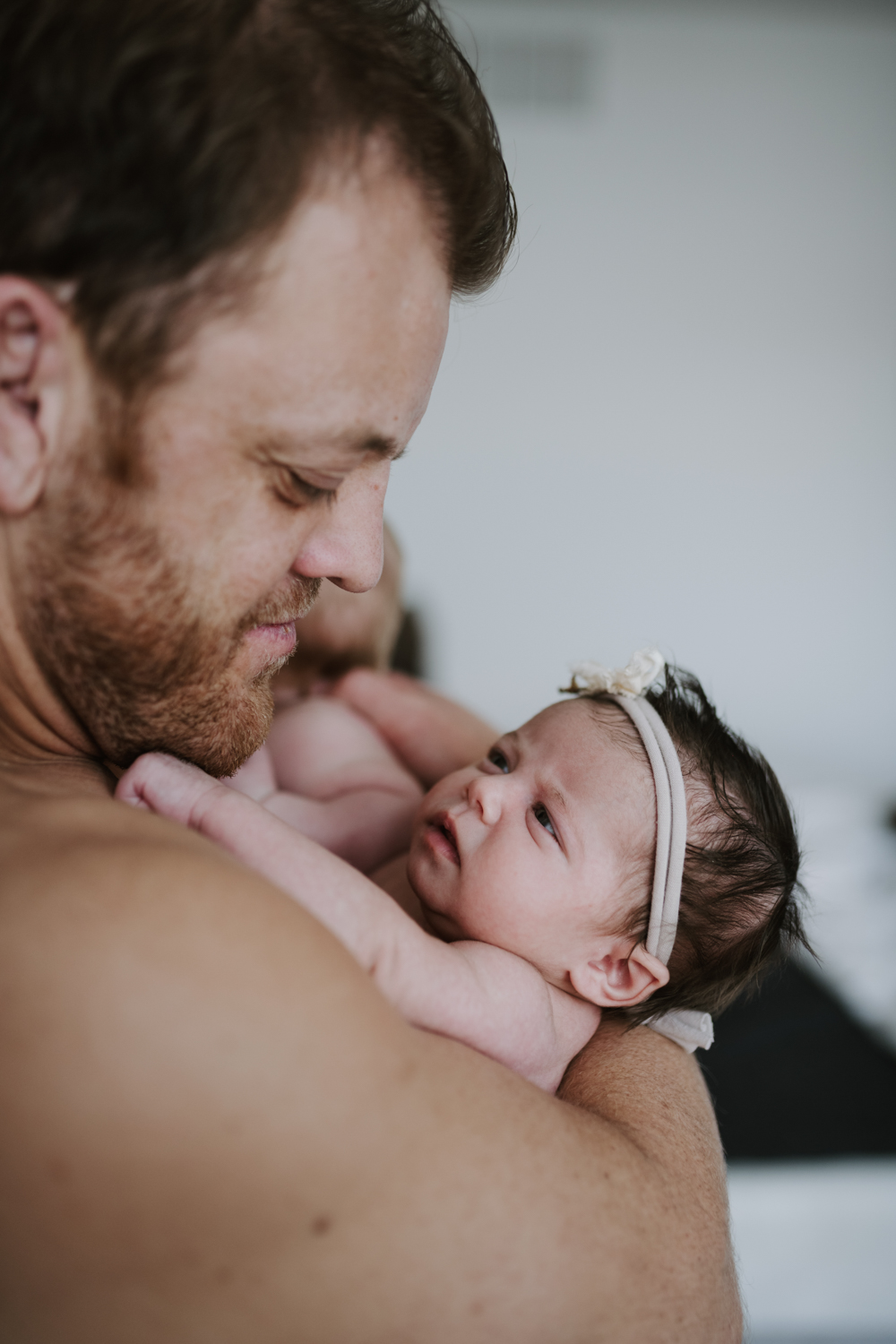 Dad holding sleeping newborn daughter while looking down at her