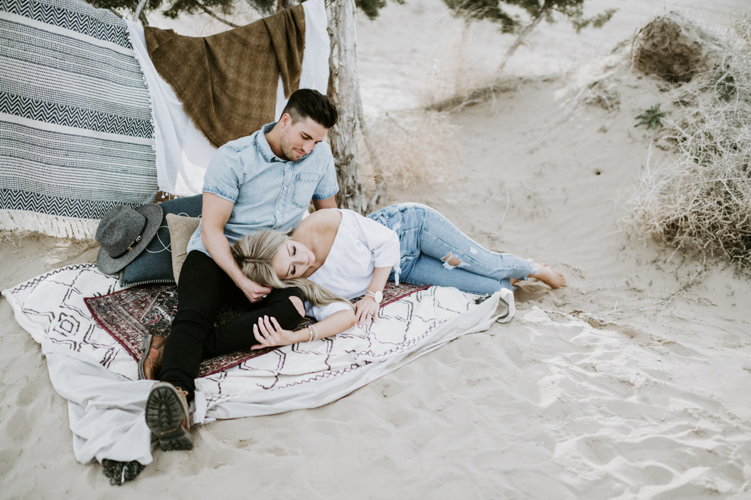 couple lying in the sand on rugs at utah sand dunes